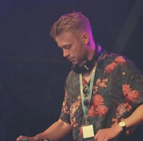 DJ Northland er i fuld fokus med at optræde på en scene bag pulten iført eksotisk sommerskjorte og headset omkring nakken